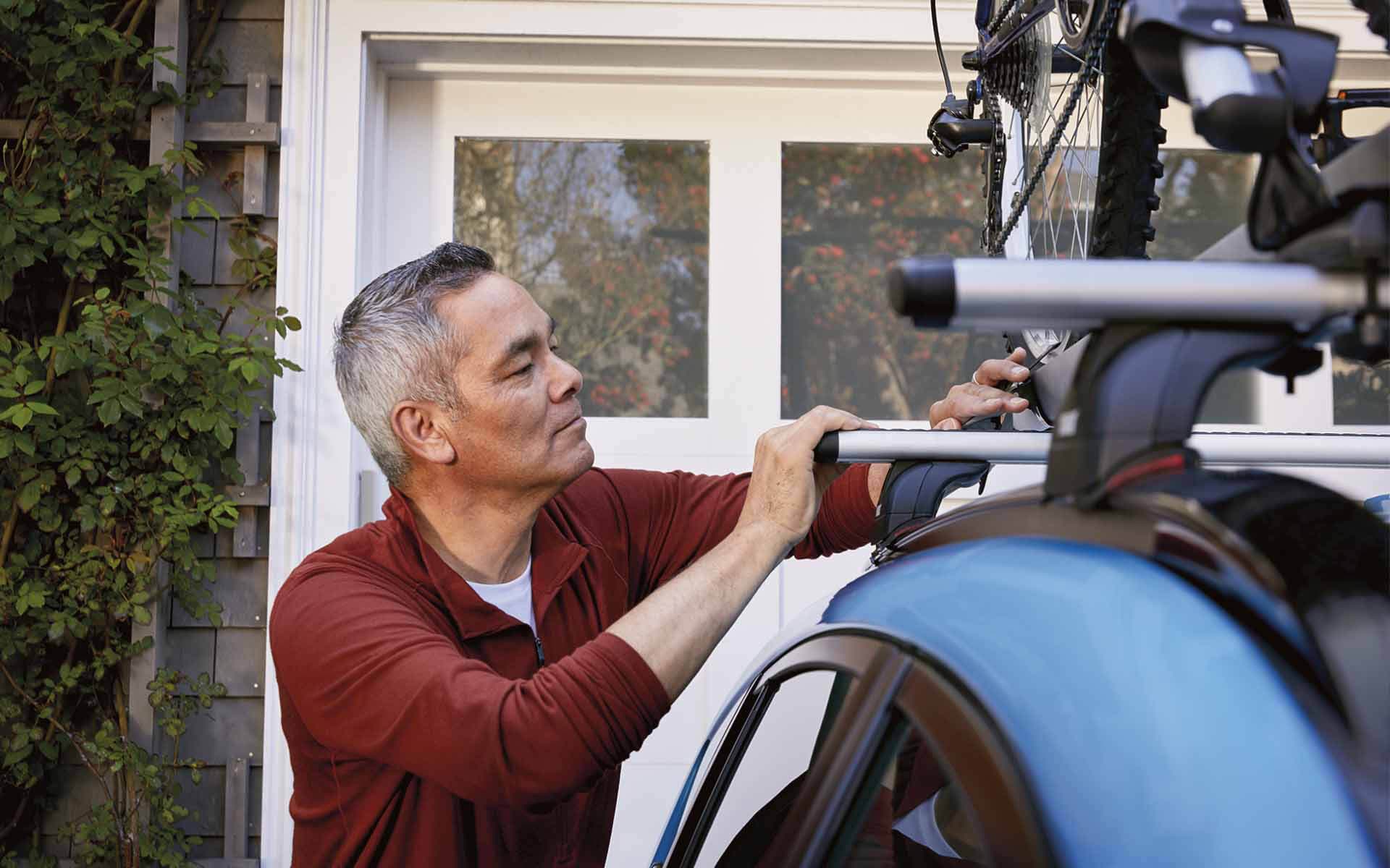 A man locking a bicycle into the Subaru Crosstrek’s roof rack