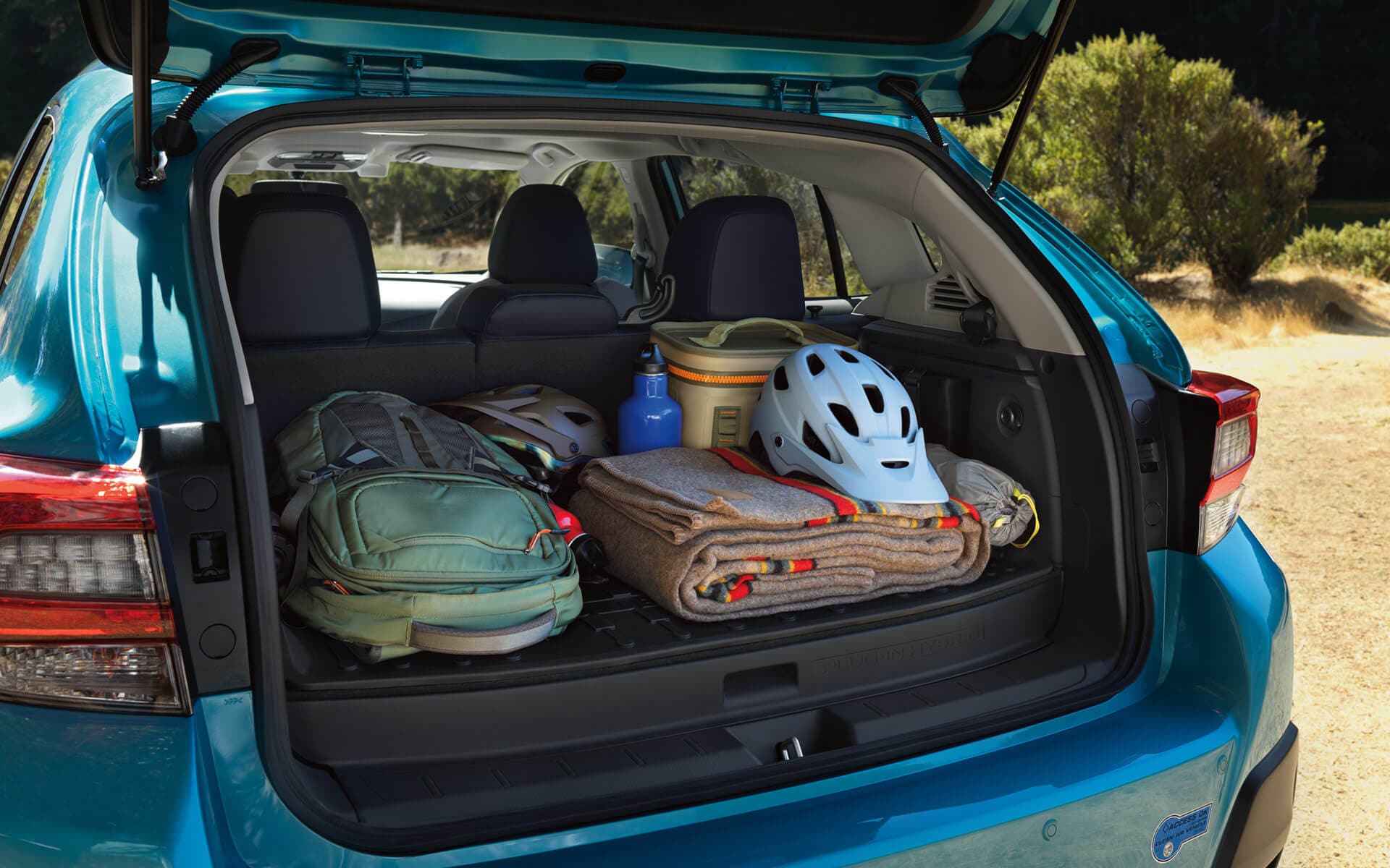 A backpack, blanket, and bike helmet in the rear cargo area of a Crosstrek Hybrid